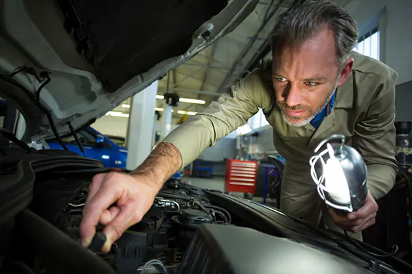 alfredo towing services company mechanic examining car with lamp1