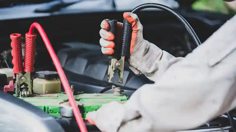 Man with wrench in the hand near a battery for jump start service