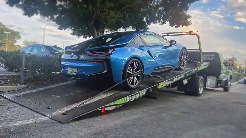 Images of a flatbed hauling a blue car in Tampa