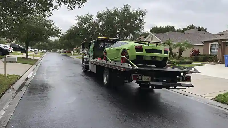 Flatbed on the road transporting a green Lamborghini.