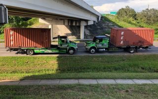 Two Flatbeds of Alfredo Towing Services transporting containers