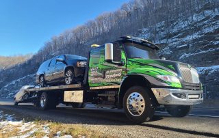 A Flatbed of Alfredo Towing Services hauling two cars.