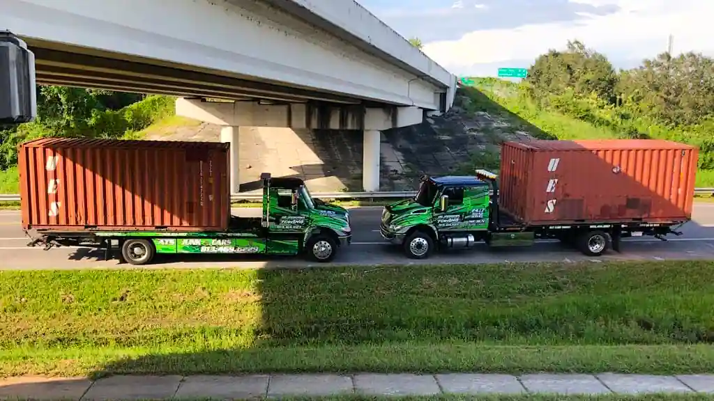 Two flatbeds on the road transporting containers.